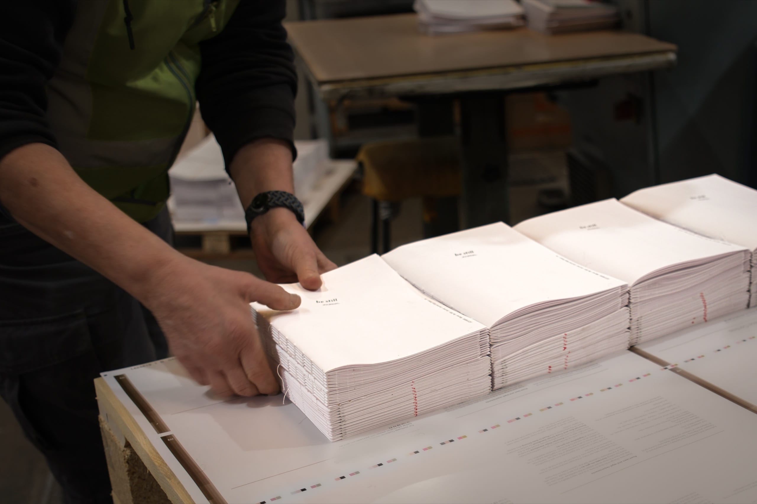 A bookbinder's hands squaring a stack of folded paper signatures at Marvel Bookbinding in Melbourne