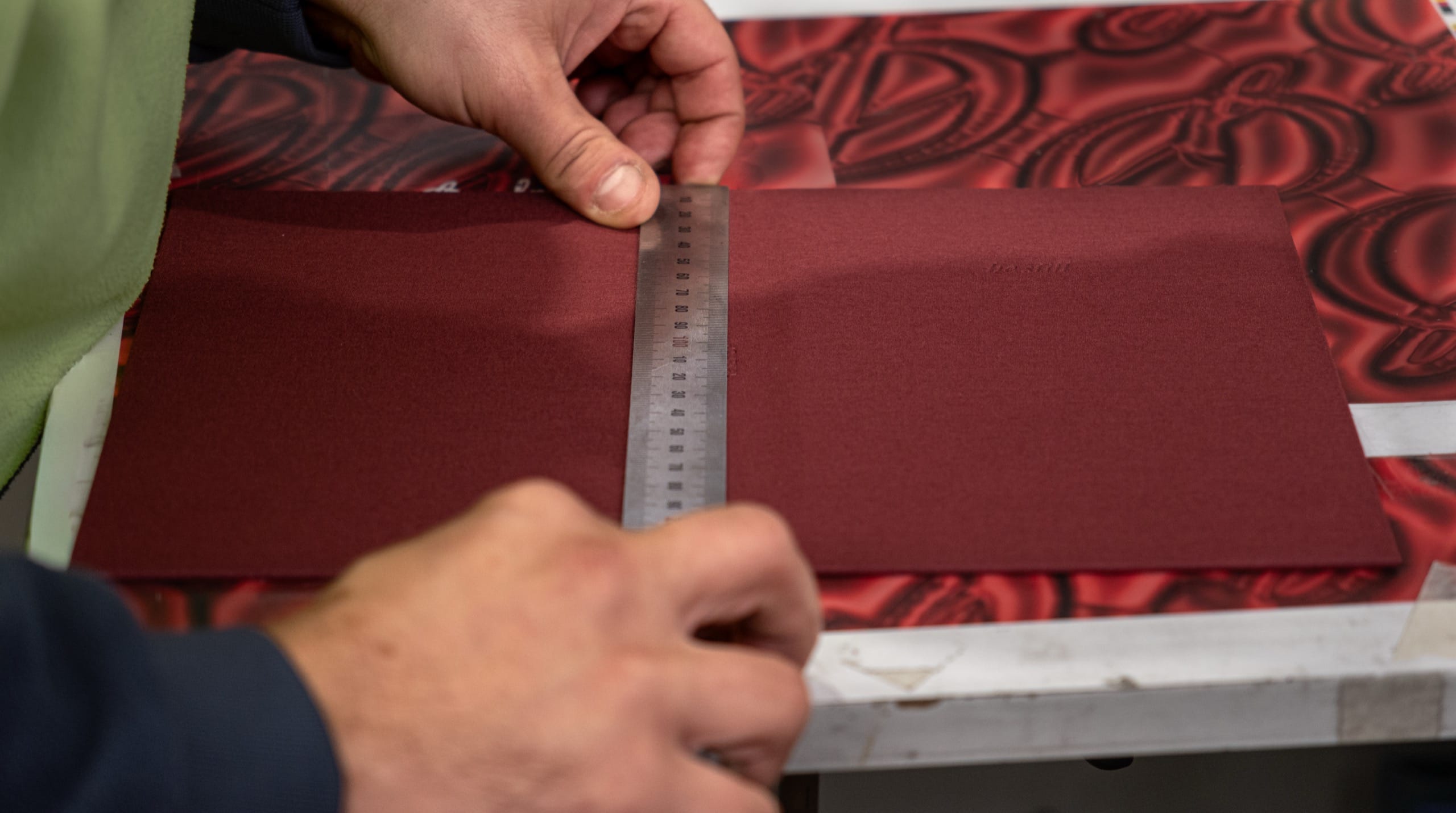 A bookbinder measuring a be still cover with a steel rule at Marvel Bookbinding in Melbourne