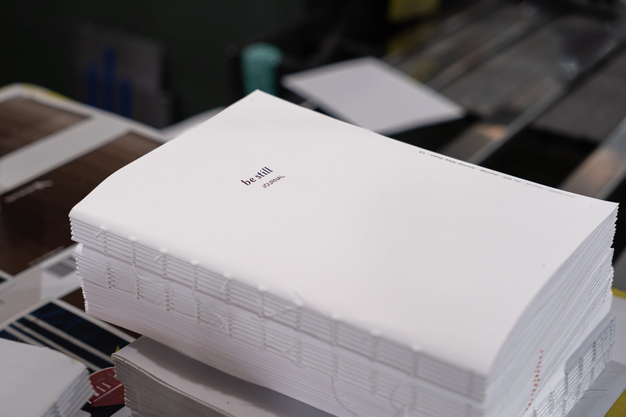A stack of folded warm-white be still signatures at Marvel Bookbinding in Melbourne